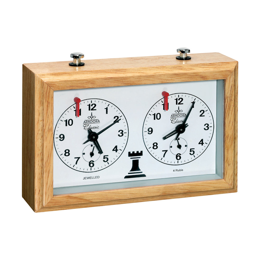 Wooden chess clock with two white analog clock faces, black hands, red flag indicators, and a black chess rook symbol between the dials