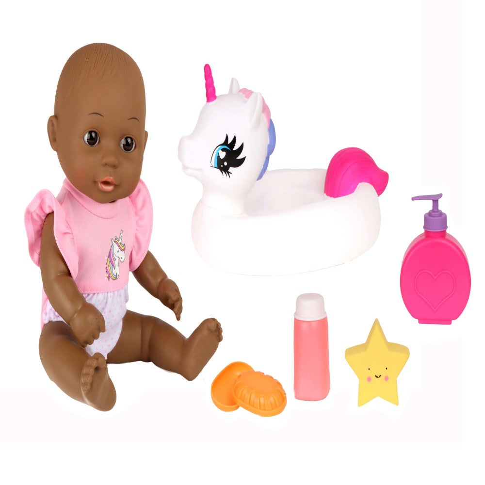 Baby doll with brown skin wearing pink unicorn shirt next to white unicorn bath floatie, pink soap bottle, yellow smiling star, and orange bath accessories