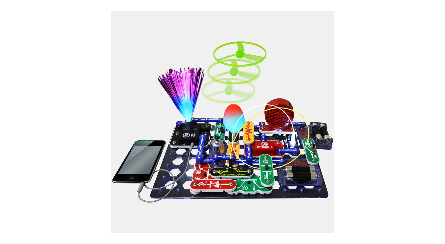 Snap Circuits LIGHT kit with electronic components on blue base board connected to smartphone, featuring illuminated fiber optic strands, green spiral tower, an