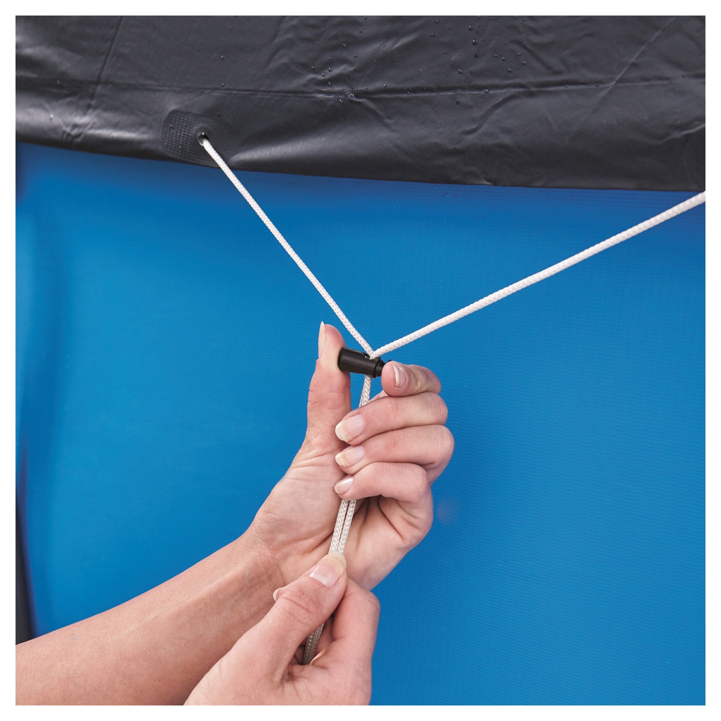 Flowclear 10' Pool Cover being held up, showing black cover and white rope attachment