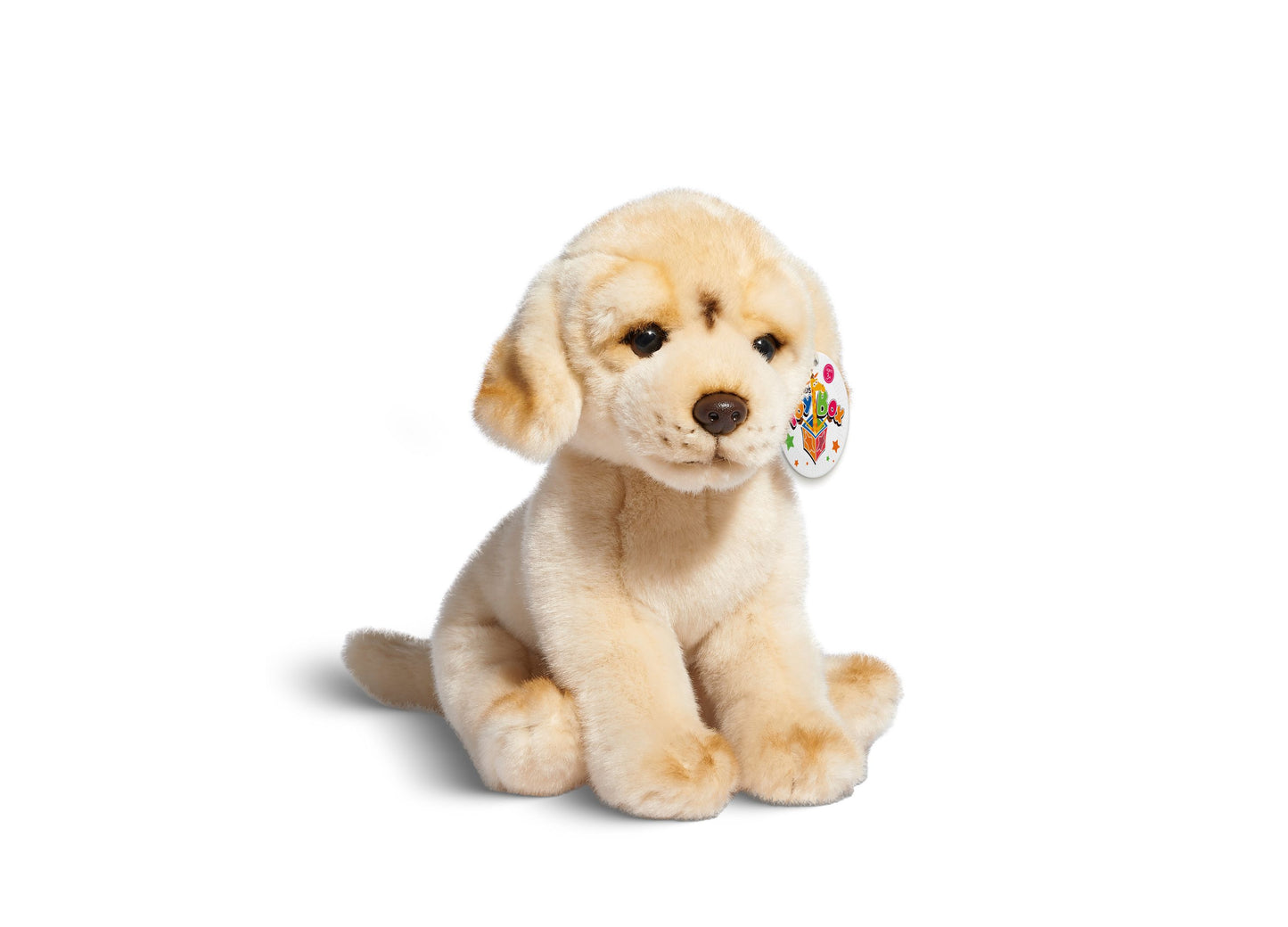 Cream-colored plush Labrador puppy with floppy ears and colorful toy tag attached to ear, seated against plain white background