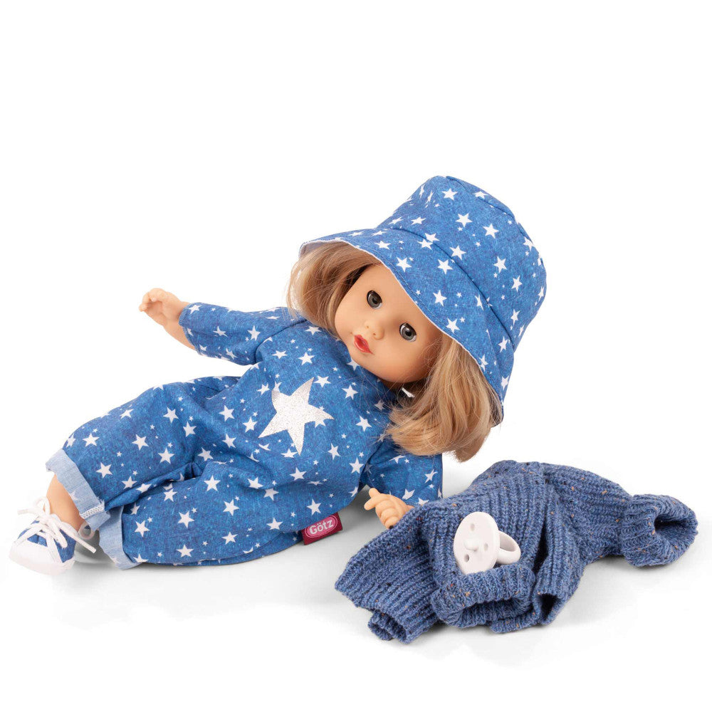 Gotz Muffin 13" baby doll with brown hair wearing blue star-print jacket, matching bucket hat, and white sneakers, positioned on white background with blue knit