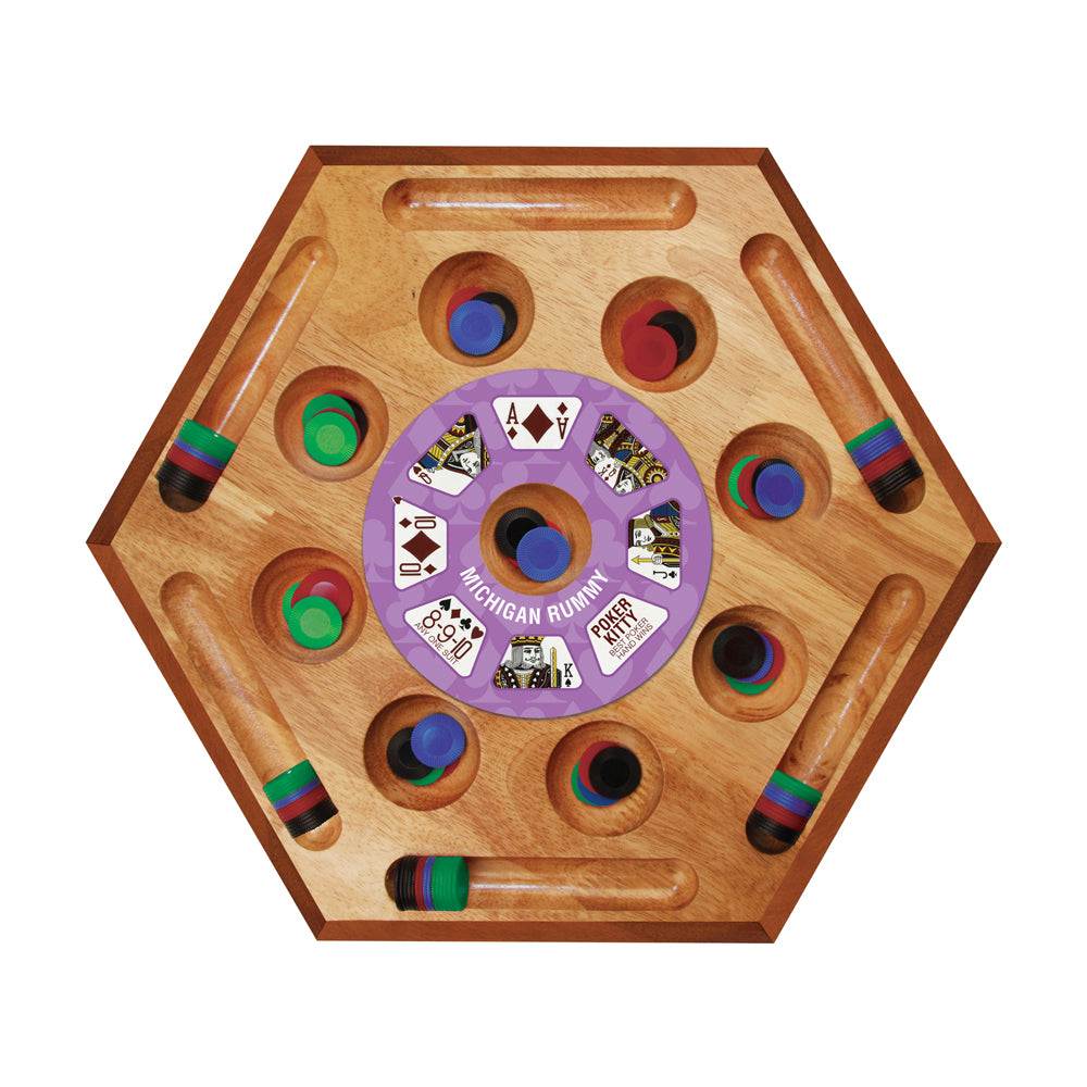 Hexagonal wooden board game with purple center wheel labeled Michigan Rummy, colorful wooden pegs in cup holders, and wooden cue sticks with striped handles