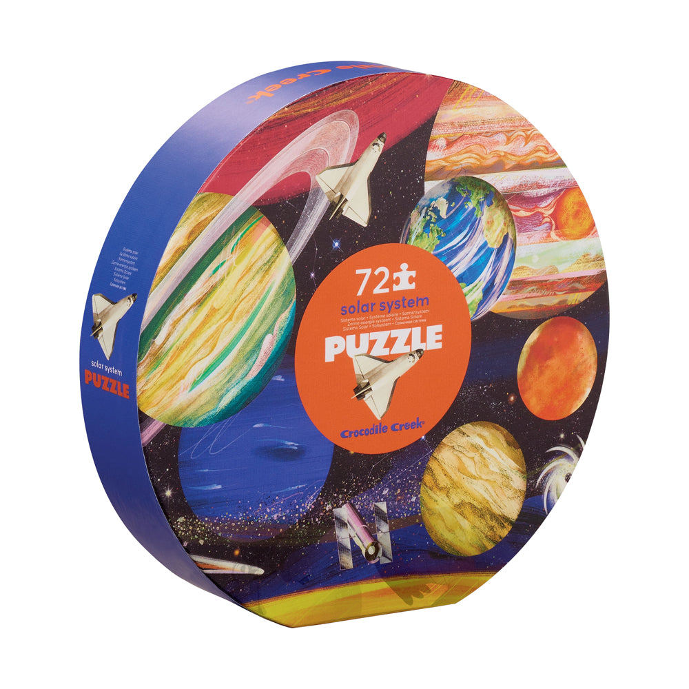 Crocodile Creek Solar System 72-piece jigsaw puzzle in round box featuring colorful illustrated planets, spacecraft, and stars against black space background