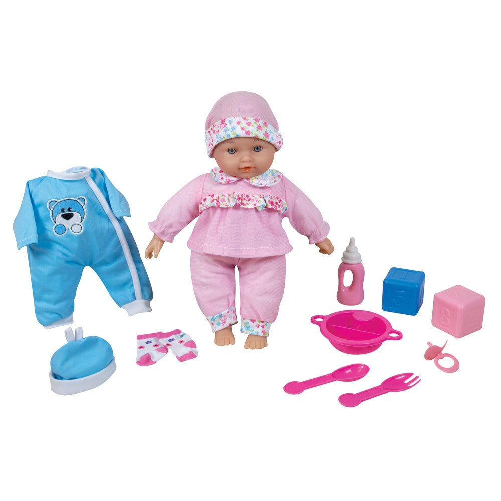 Baby doll in pink outfit with floral hat, surrounded by accessories including blue outfit, bottle, bowl, utensils, and blocks