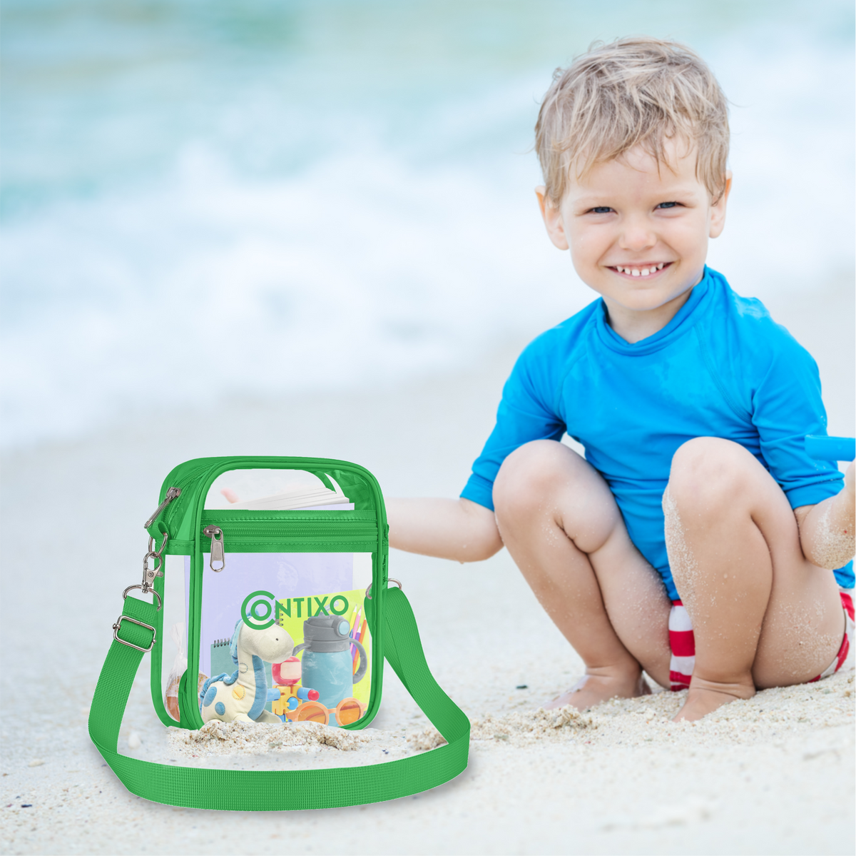 Modeled by a child wearing blue shirt on beach, holding green Contixo clear stadium bag with adjustable shoulder strap