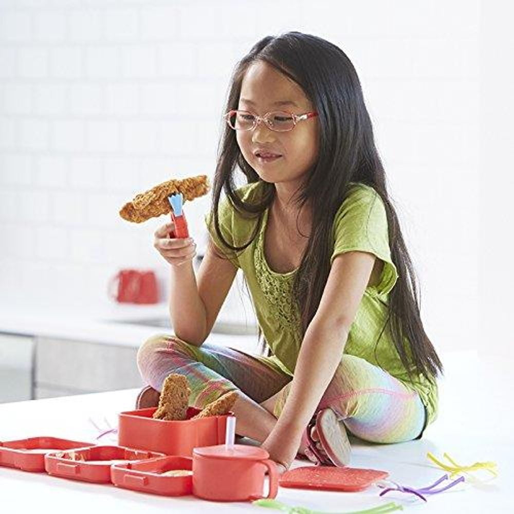 Child modeled by a child using red Crabby Grabby utensils to pick up pretend food items from a red serving tray