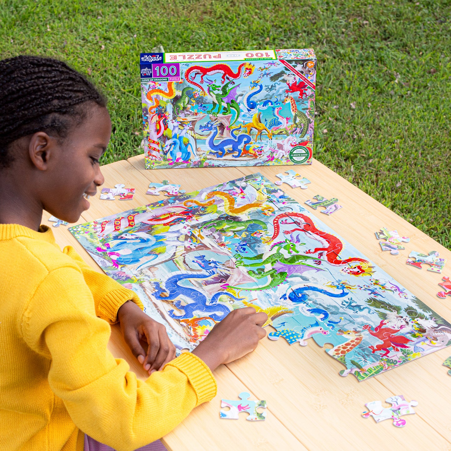 Child assembling 100 Piece Puzzle: Love of Dragons with colorful dragons and fantasy creatures