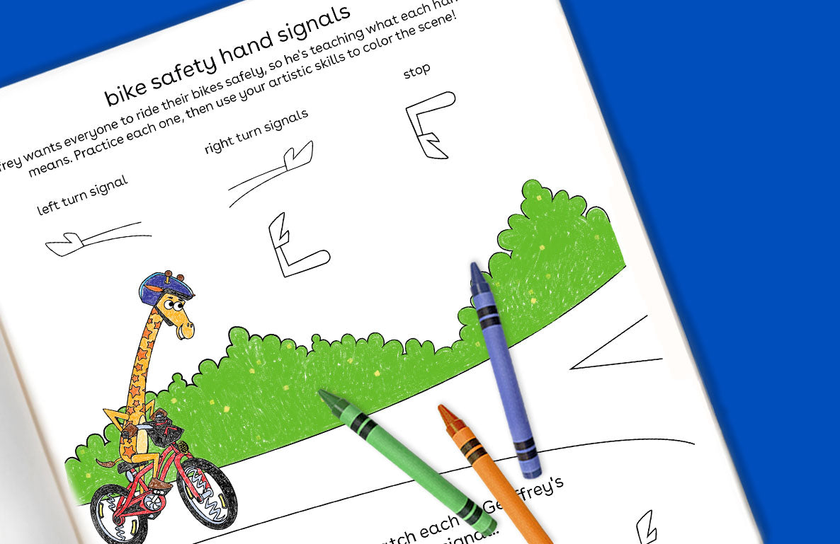 Educational activity page showing bike safety hand signals with cartoon giraffe on bicycle, green bushes, and colored crayons positioned to demonstrate left tur