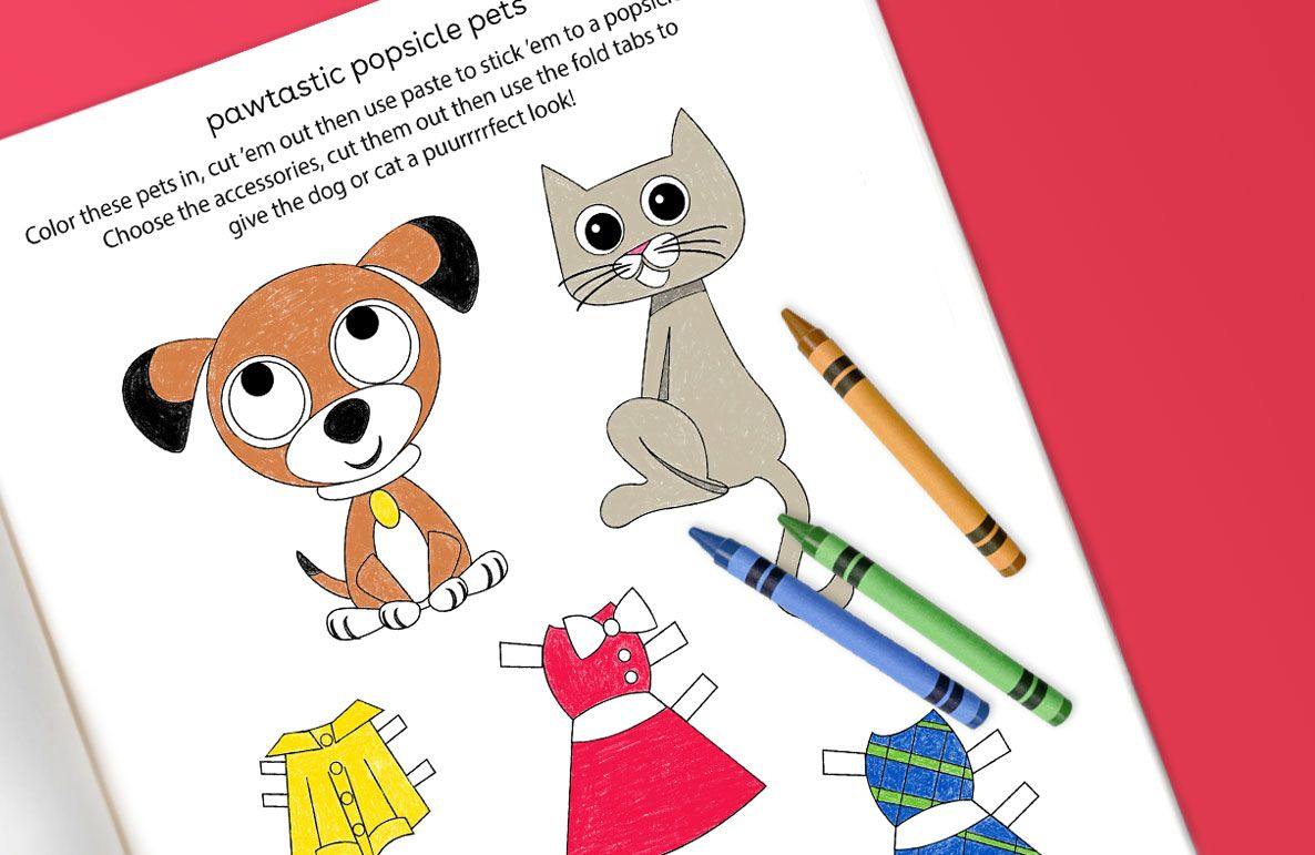 Coloring page with illustrated dog and cat and cut-out clothing accessories, crayons nearby on pink background