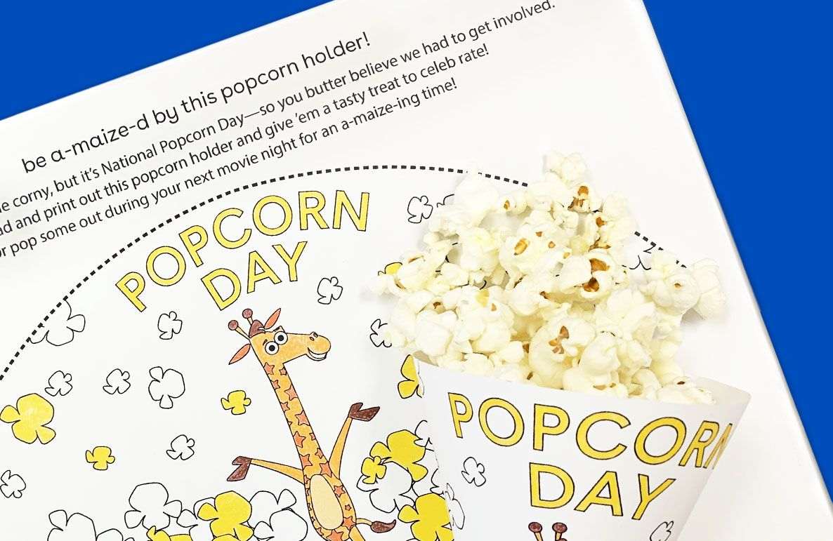 Blog article page about National Popcorn Day featuring illustrated giraffe surrounded by popcorn kernels and popcorn holder product with white popcorn on blue b