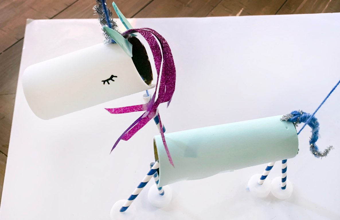 DIY unicorn marionette craft made from paper cups, glitter, and string, displayed on white background