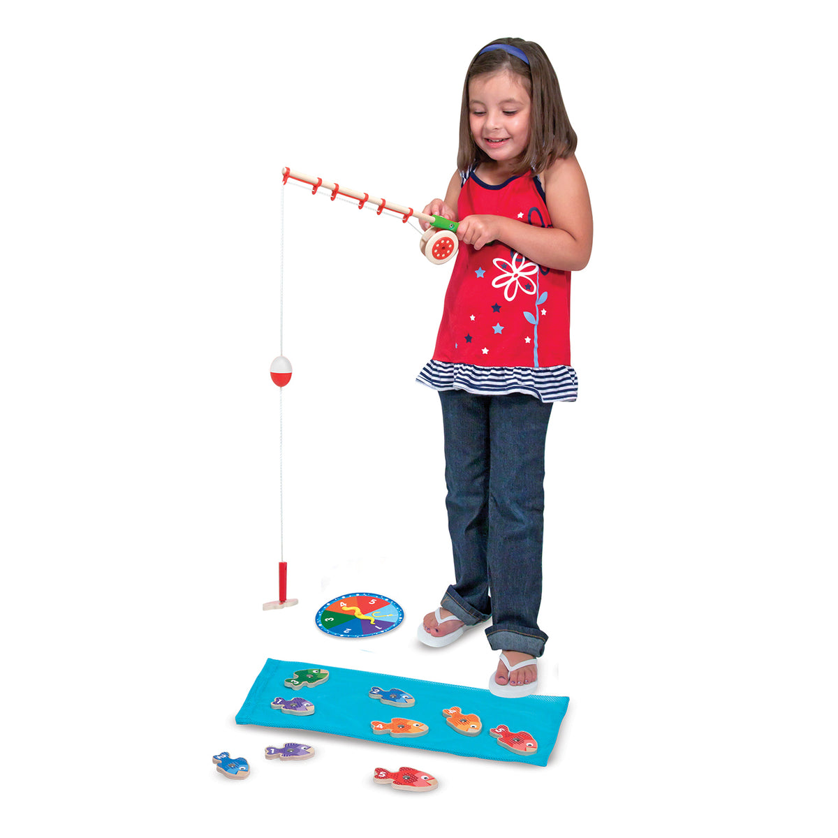 Girl playing with Catch & Count Magnetic Wooden Fishing Game, red reel and colorful fish pieces on blue mat