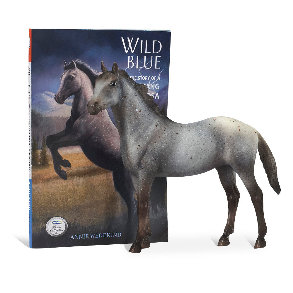 Gray horse figurine standing next to Wild Blue book by Annie Wedekind, featuring horses on cover