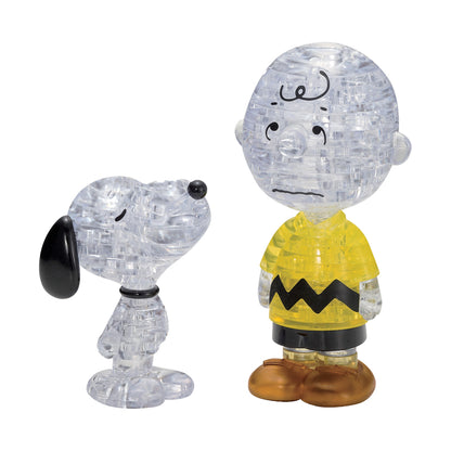 Two clear crystal puzzle figurines of Snoopy and Charlie Brown from Peanuts, with black facial features and details; Charlie Brown wears a yellow shirt with bla