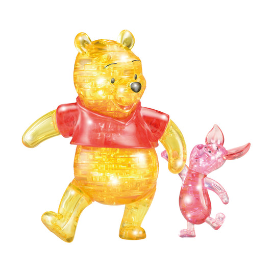 Yellow translucent 3D crystal puzzle of Winnie the Pooh wearing a red shirt, next to a smaller pink translucent puzzle of Piglet