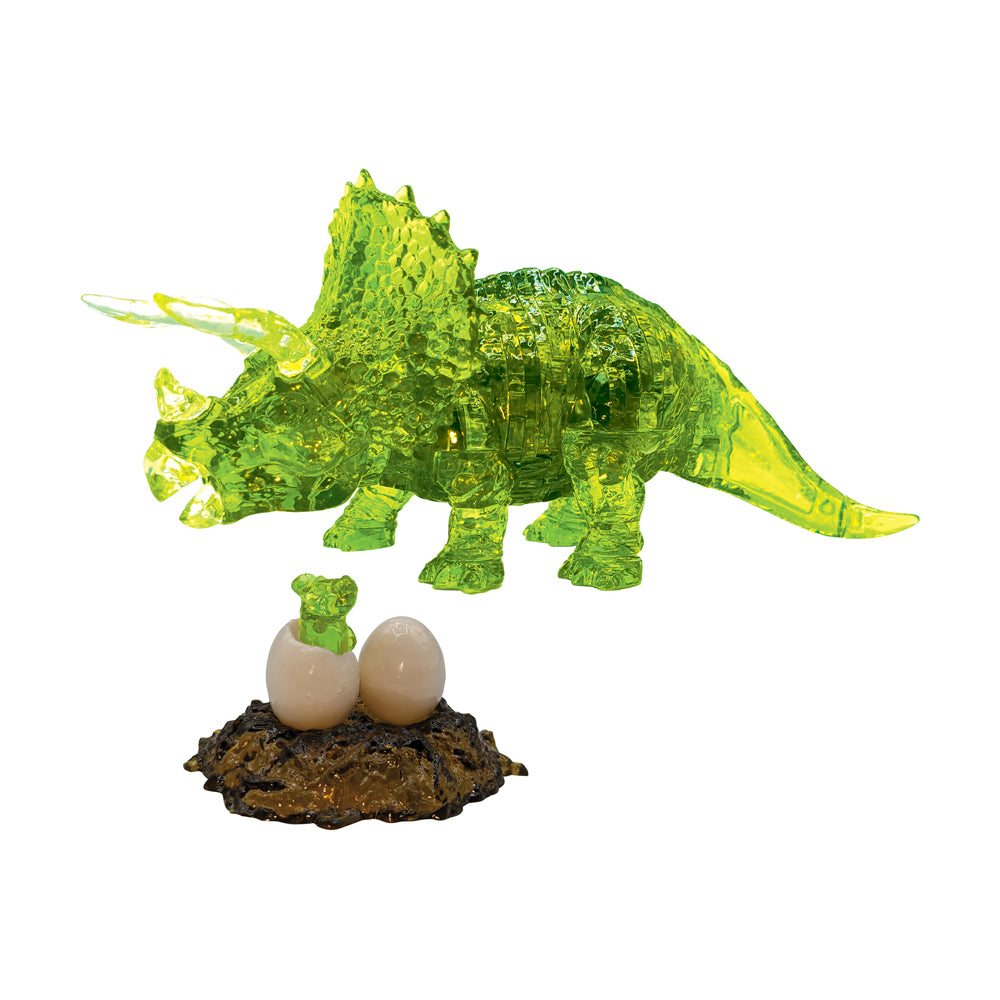 Green translucent crystal puzzle triceratops with raised frill and horns, displayed above a brown nest base with two cream-colored eggs and a small green baby t