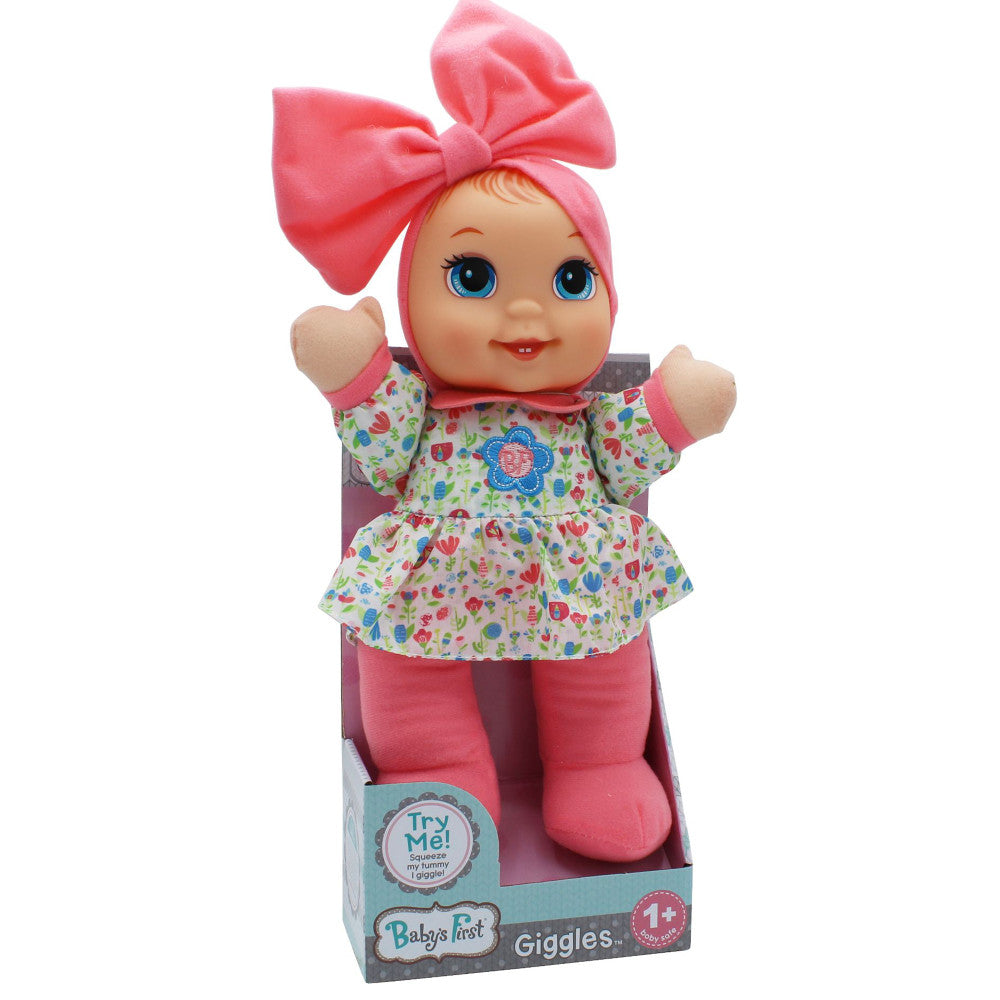 Baby's First Giggles doll with pink bow, blue eyes, floral print dress, and pink legs in packaging