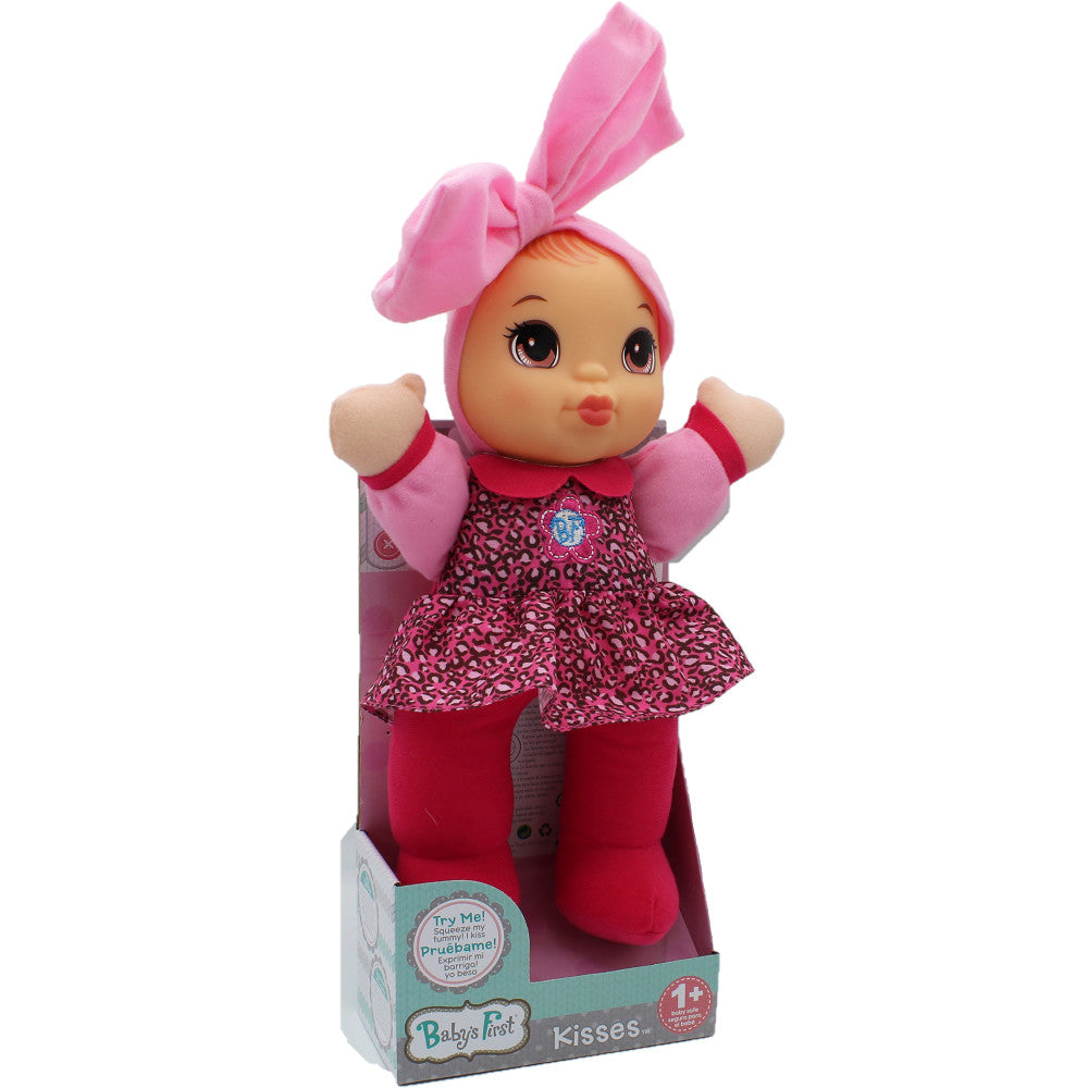 Baby's First Kisses doll with pink bow headpiece, pink and magenta patterned dress, red tights, and cream-colored mittens in packaging