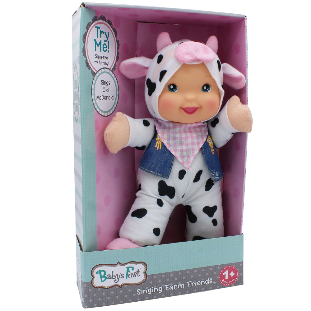 Baby's First Singing Farm Friends cow doll in packaging, white plush with black spots, pink ears and nose, wearing pink gingham bandana and denim vest