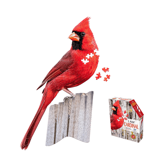 Red cardinal-shaped jigsaw puzzle displayed assembled on stand with loose puzzle pieces and product box showing completed cardinal image