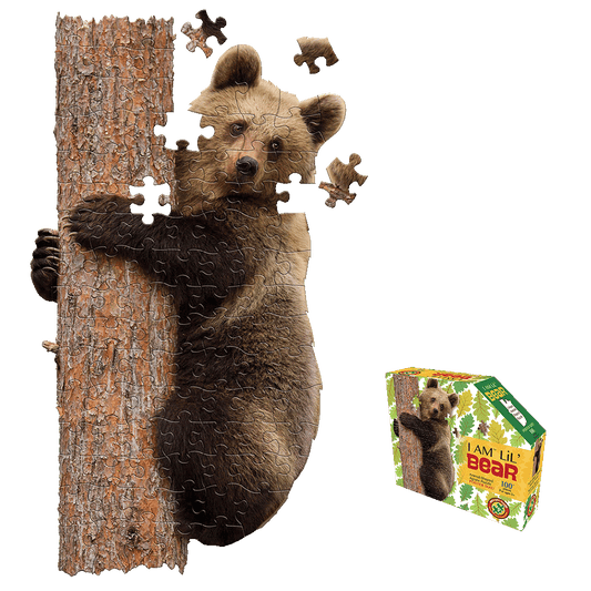 Bear cub climbing tree trunk puzzle with loose pieces floating above, shown with product box featuring I AM LiL' BEAR branding