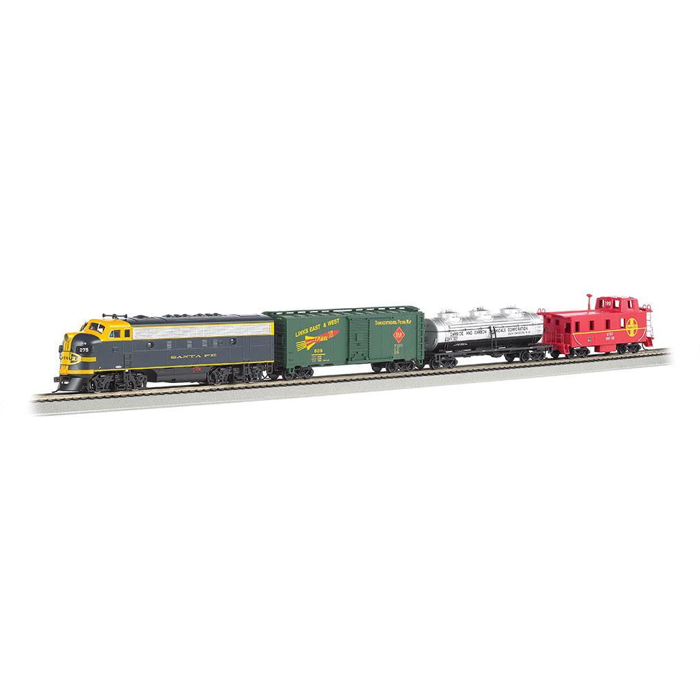 Bachmann Trains Thunder Chief HO scale electric train set with yellow and gray Santa Fe locomotive, green freight cars, silver tank car, and red caboose on gray