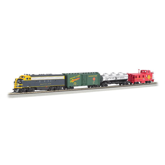 Bachmann Trains Thunder Chief HO scale electric train set with yellow and gray Santa Fe locomotive, green freight cars, silver tank car, and red caboose on gray