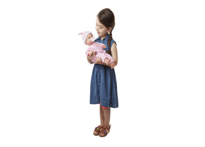 Girl holding Melissa & Doug Mine to Love Luke baby doll in pink outfit
