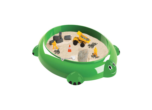 Green turtle-shaped sandbox with sand, yellow dump truck, construction worker figures, traffic cone, rocks, and shovel
