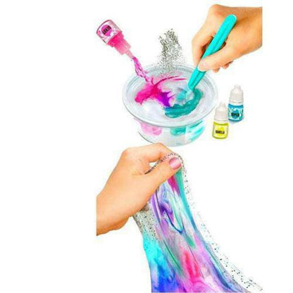 Hands modeled by a child mixing colorful slime in a clear bowl with a blue tool, holding sparkly tie-dye slime, with pink applicator bottle and small ingredient