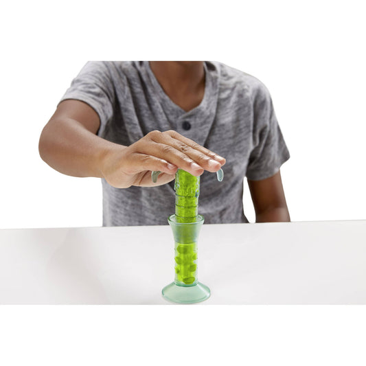 Child modeled by a child squeezing green slime from a clear cylinder toy with suction cup base