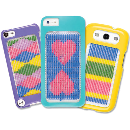Three colorful phone case craft kits in purple, turquoise, and yellow, each featuring a needlepoint design with multicolored pixelated patterns on the back