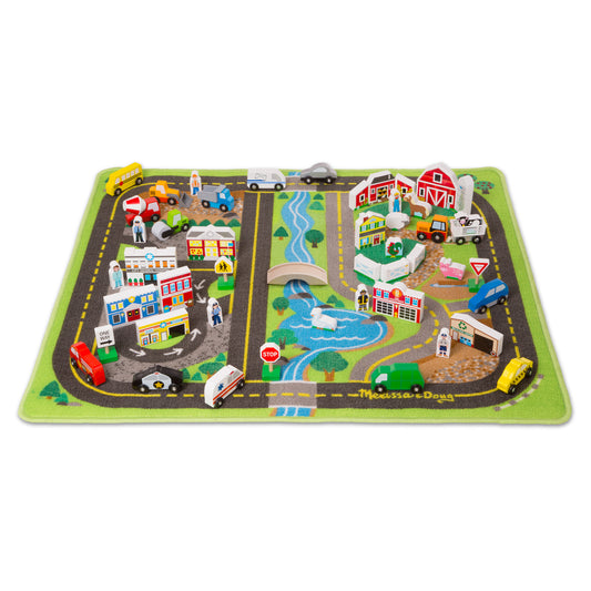 Deluxe road rug play set with green border featuring town scenes, roads with yellow lines, wooden vehicle and building accessories, trees, water, and figures