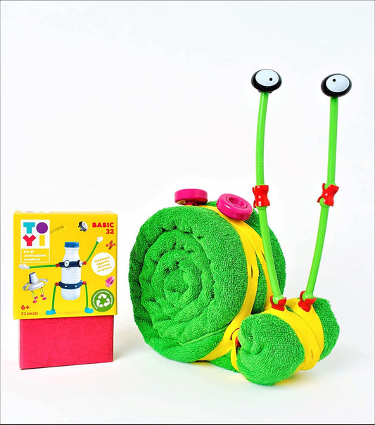 Green plush snail toy with yellow band, pink accents, and two green stems with eyeball toppers; displayed with yellow product box for Toyi 32-piece building kit