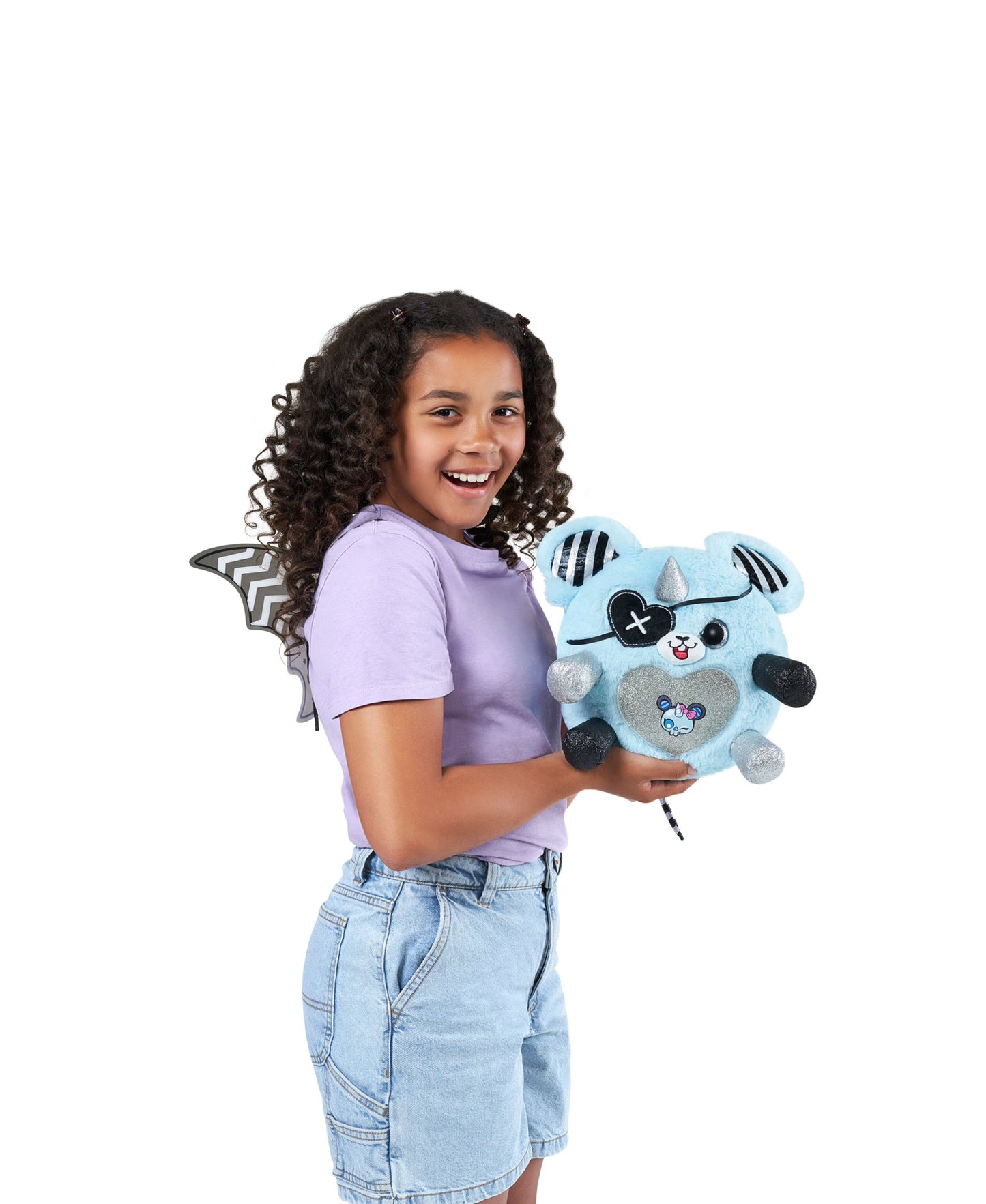 Light blue plush Monstercorn character with black and white striped wings, held by a child modeled on model wearing purple shirt and denim skirt