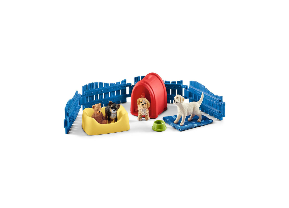 Puppy pen playset with blue fencing, red dome shelter, yellow bed, blue mat, green food bowl, and four dog figurines on white background