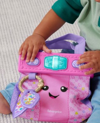 Fisher-Price Laugh & Learn On-the-Go Learning Purse in pink with interactive accessories, held by child's hands