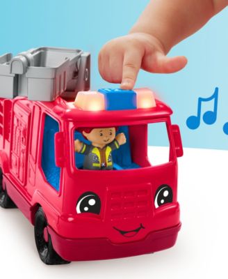 Red fire engine toy with smiling face and child's hand placing blue block on roof