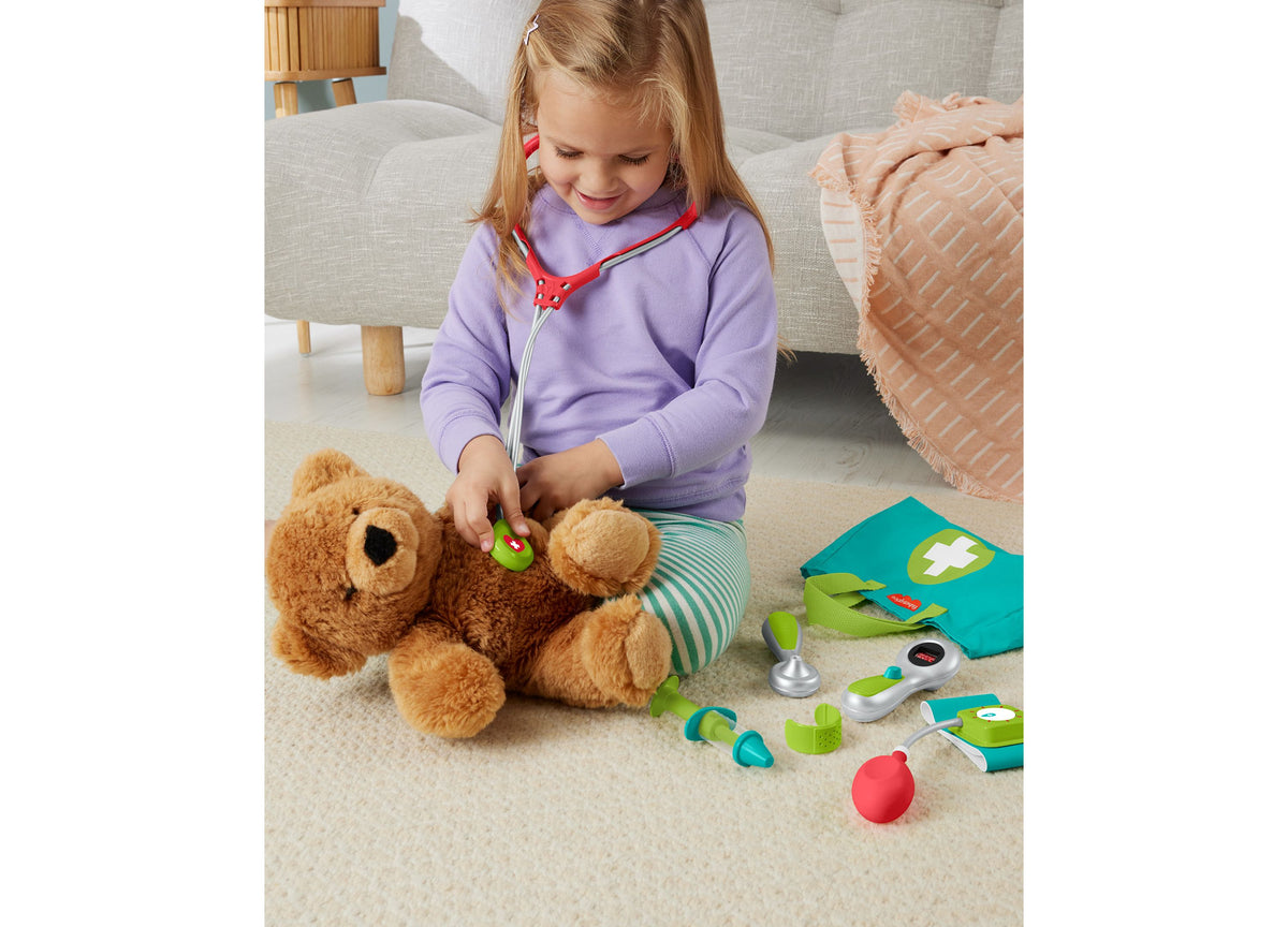 Girl playing doctor with Fisher-Price Medical Kit 7-Piece Set, including stethoscope and tools with teddy bear patient