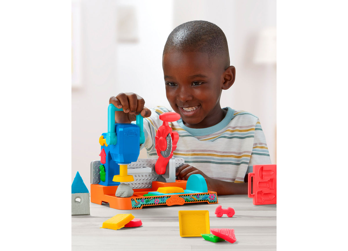 Boy playing with Play-Doh Stamp N Saw Tool Bench set featuring blue, red, orange, and yellow components
