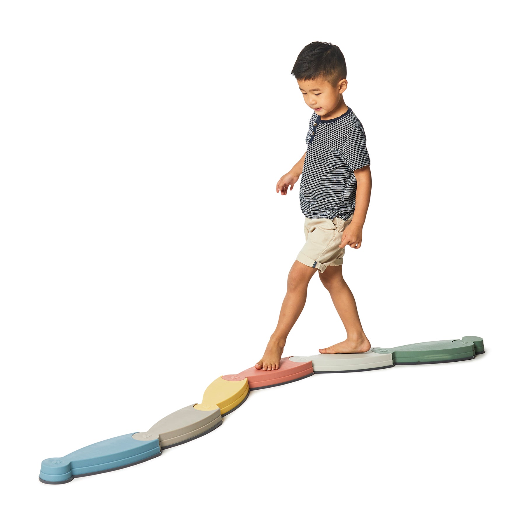 Child modeled on a colorful segmented balance pathway set, walking across connected blue, yellow, gray, red, and green curved modules on a plain background