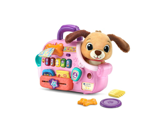 Pink interactive puppy carrier with plush tan and brown puppy, colorful activity buttons, numbered keys, musical elements, and included accessories on plain bac