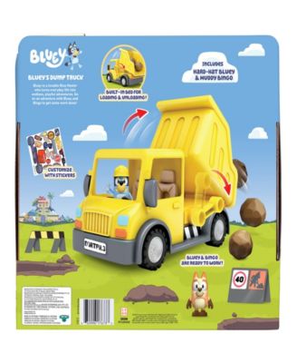 Bluey's Adventure Series yellow dump truck with exclusive hard-hat Bluey and muddy Bingo figures on green grass backg...