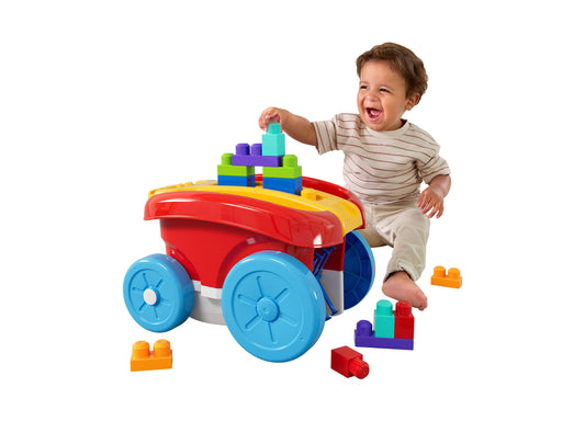 Toddler on model playing with colorful block scooping wagon toy with blue wheels, stacking building blocks on red cart