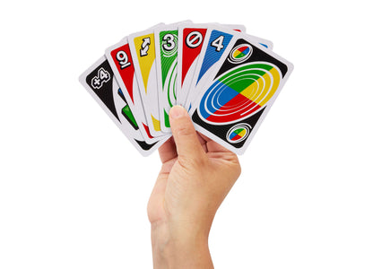 Hand holding fanned Mattel UNO Spin card game cards showing numbered and action cards in red, yellow, green, and blue...