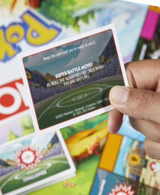 Pokémon Monopoly Edition Board Game card held in hand over colorful game board with yellow, blue, and green packaging