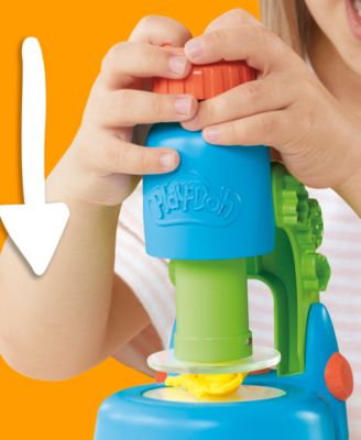 Child's hands holding blue Play-Doh Light and Look Microscope with green base and yellow accents