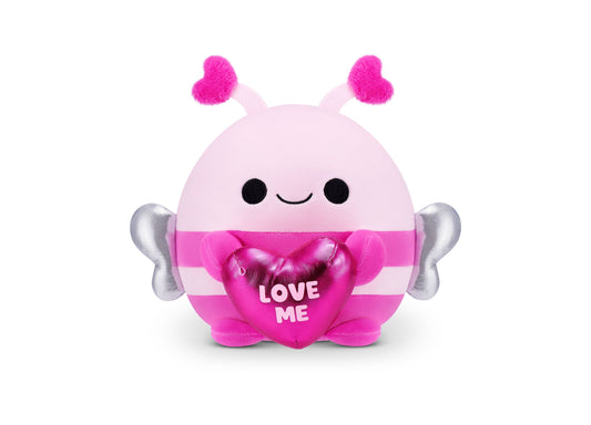 Pink and magenta plush Snackles bumblebee with fuzzy hot pink antennae, silver wings, black dot eyes, closed smile, and heart-shaped accessory reading LOVE ME