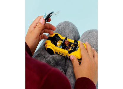 LEGO City Yellow Taxi Car 60487 toy being held by child hands against blue background